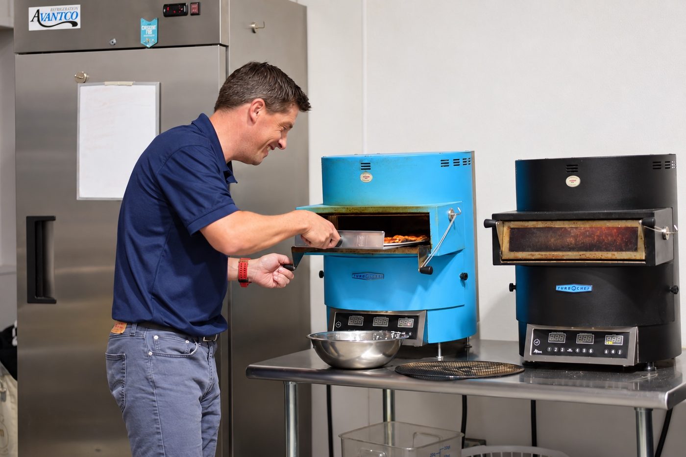 A Hitters team member sliding a pizza into the kitchen oven